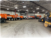 Row of White and Orange Gravel Trucks Parked Inside Facility