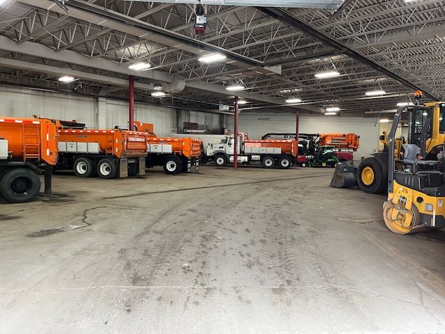 Row of White and Orange Gravel Trucks Parked Inside Facility