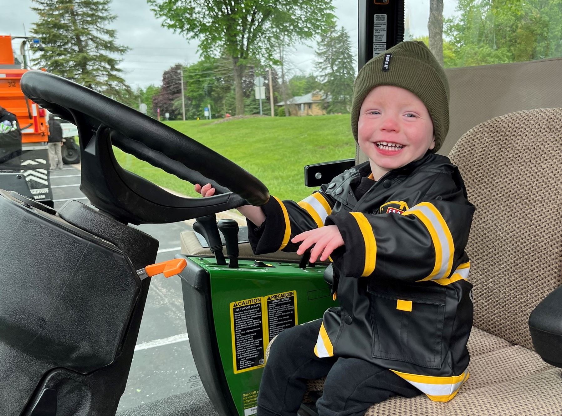 Child sitting at the wheel of a truck smiling at touch a truck